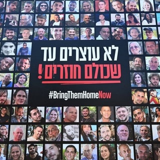 Bilder der von der Hamas entführten israelischen Geiseln sind an einer Mauer zu sehen mit dem Spruch „#BringThemHomeNow“