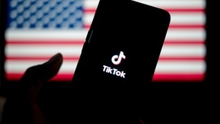 TikTok auf einem Smartphone, im Hintergrund die Flagge der USA. Die App wurde wegen eines Verbots abgeschaltet.