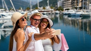 Reiche junge Menschen nach dem Shoppen im Yachthafen: Superreiche fordern höhere Steuern für sich selbst.