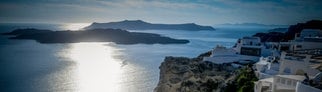 Überblick über Santorini: Man sieht einen Hotelpool und dahinter das Meer vor dunkelblauem Himmel.