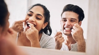 Frau und Mann nutzen Zahnseide, was ihr Schlaganfallrisiko senkt