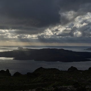 Sonnenstrahlen beleuchten das vulkanische Eiland Nea Kameni, das zur Insel Santorini gehört, die gerade von Erdbeben betroffen ist. Derzeit bebt die Erde auf der Insel fast im Zehn-Minuten-Takt. Das betreffende Beben erreichte mit Stärke 5 einen vorläufigen Höchstwert.