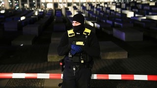 Ein Polizist steht vor dem abgesperrten Mahnmal für den Holocaust in Berlin. Es gab dort eine Messerattacke.