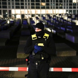 Ein Polizist steht vor dem abgesperrten Mahnmal für den Holocaust in Berlin. Es gab dort eine Messerattacke.