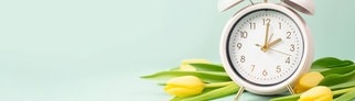 Eine Uhr und Tulpen symbolisieren den Frühling und die Sommerzeit.