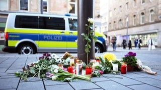 Kerzen und Blumen liegen an einer Straßenbahnhaltestelle auf den Planken in Mannheim, wo ein Mann mit seinem Auto zwei Menschen getötet hat.