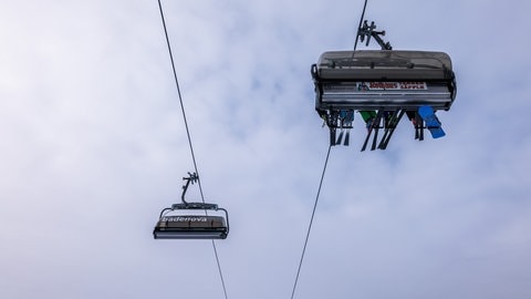 Wintersportler sitzen mit ihren Sportgeräten in einer Sessellift-Gondel der Feldbergbahn und lassen sich den Berg hinaufbringen.