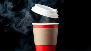 Ein roter, dampfender Pappbecher, der für To-go-Getränke wie Tee oder Kaffee genutzt wird