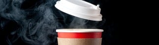 Ein roter, dampfender Pappbecher, der für To-go-Getränke wie Tee oder Kaffee genutzt wird