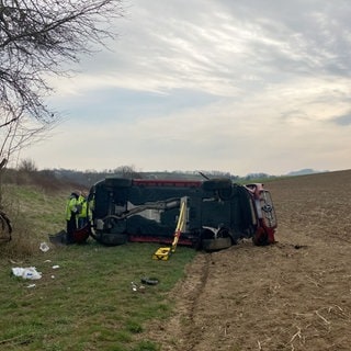 Ein Fahrzeug liegt an der Anschlussstelle Bretzfeld auf der A6 in einem Feld. Bei einem schweren Verkehrsunfall auf der Autobahn 6 östlich von Heilbronn sind zwei Menschen gestorben – vier weitere wurden schwer verletzt.