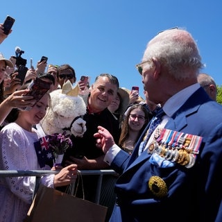 König Charles III. spricht mit einem Alpaka, das ihn gerade angeniest hat, am Australischen Kriegsdenkmal in Canberra