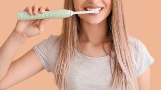 Frau putzt Zähne mit elektrischer Zahnbürste