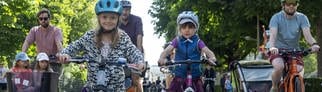 Kinder fahren mit ihren Eltern auf der Straße mit ihren Fahrrädern