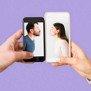 Zwei Menschen halten Smartphones aneinander. Darauf zu sehen sind ein Mann und eine Frau, die einen Kussmund formen.
