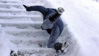 Mensch rutscht auf einer vereisten Treppe aus