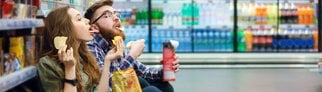 Mann und Frau naschen im Supermarkt