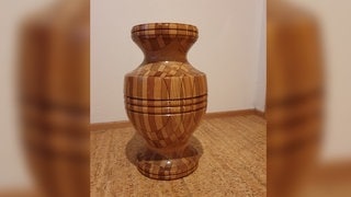 Eine große Bodenvase aus Holz steht in einer Ecke.