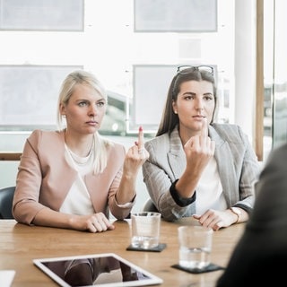 Zwei Frauen zeigen ihrem Chef den Mittelfinger