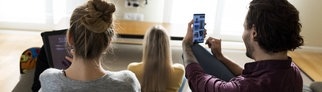 Menschen mit unterschiedlichen technischen Geräten wie Smartphone, Tablet und Fernseher