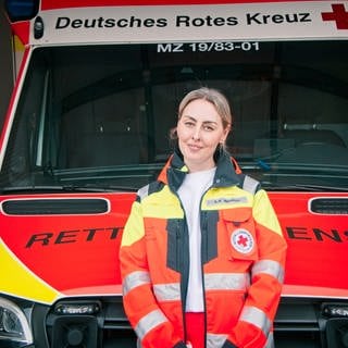 Anne Mendoza steht vor einem Krankenwagen. Sie ist Notfallsanitäterin und Leiterin der Rettungswache in Nieder-Olm, in der Nähe von Mainz. Seit sie 18 ist, fährt sie Rettungseinsätze.Sie sagt, Gewalt gegen Rettungskräfte kennt jede Einsatzkraft.