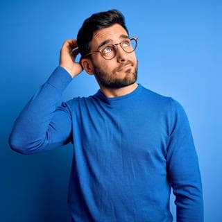 Junger Mann mit Brille und blauem Pullover schaut nachdenkend in die Luft. Symbolbild für Sätze, die du nur verstehst, wenn du Dialekt sprichst.