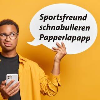 Ein junger Mann hält ein Handy in der einen Hand und in der anderen Hand eine Sprechblase mit den Wörtern Sportsfreund, schnabulieren und Papperlapapp.