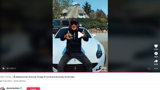 Screenshot eines Videos von Dieter Bohlens Tiktok Kanal. Dabei sitzt er vor einem Haus auf der Motorhaube eines weißen Ferrari