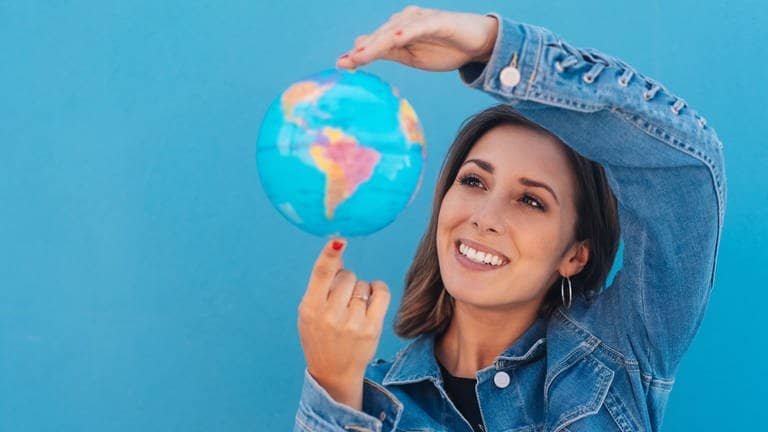 Junge Frau hält einen Globus in der Hand. Symbolbild für deutsche Wörter, die auch in anderen Sprachen vorkommen.