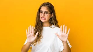 Junge Frau mit ablehnendem Gesichtsausdruck und den Händen vor dem Körper. Symbolbild für die Anleitung zum Widerspruch bei Facebook und Instagram, die Fotos zum KI-Training nutzen.