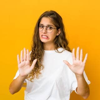 Junge Frau mit ablehnendem Gesichtsausdruck und den Händen vor dem Körper. Symbolbild für die Anleitung zum Widerspruch bei Facebook und Instagram, die Fotos zum KI-Training nutzen.