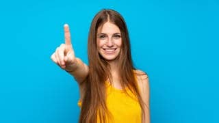 Junge Frau zeigt mit dem Finger die Zahl Eins in der Luft. Symbolbild für unübersetzbare deutsche Wörter, die in unserer Sprache einzigartig sind.