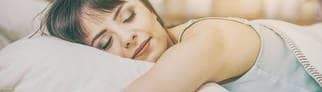 Eine Frau liegt gemütlich auf ihrem Kopfkissen im Bett