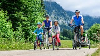 Kinderfahrradanhänger bei Stiftung Warentest: Alle fallen durch. Das Bild zeigt eine Familie auf Fahrradtour