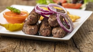 Kroatische Cevapcici angerichtet auf einem Teller