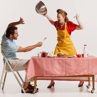 Symbolbild: Strategische Inkompetenz in Beziehungen. | Mann und Frau im Stil der 60er streiten beim Abendessen