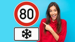 Frau zeigt lachend auf Verkehrszeichen mit Schneeflocke und Tempo 80. Gilt das Schild nur im Winter?