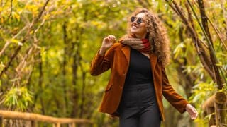 Frau macht einen Spaziergang im Herbst durch bunte Blätter