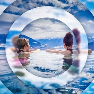 Zwei junge Frauen in einem Pool mit Ausblick auf ein Alpenpanorama Symbolbild für Gewinnspiel: Gutschein für Urlaub in Südtirol gewinnen.