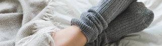 Füße einer Frau mit Socken im Bett.