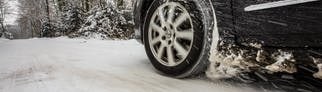 Ein Auto fährt mit Winterreifen, die ab Oktober 2024 ein Alpine-Symbol benötigen, auf einer Straße mit geschlossener Schneedecke.