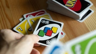 Kartenspiel Uno, verschiedene Spielkarten in der Hand eines Spielers. Symbolbild für unbekannte Spielregeln beim Spiele-Klassiker.