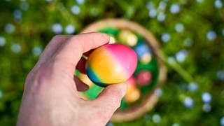 Mann hält ein Osterei in der Hand. Symbolbild für coole Abwesenheitsnotizen für den Urlaub.