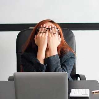 Frau versteckt ihr Gesicht hinter ihren Händen. Symbolbild: Kann das Gehirn durch Corona schneller altern?