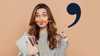 Junge Frau hat einen Stift zwischen Lippen und Nase und zieht denkend die Augenbraue hoch. Mit dem Finger deutet sie auf ein Apostroph. Symbolbild fürs Apostroph im Deutschen. Wann wird es gesetzt? Tipps zur Rechtschreibung.