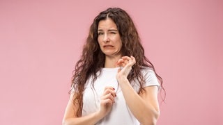 Junge Frau mit angeekeltem Gesichtsausdruck. Symbolbild zum Überblick: Schimmel an Lebensmitteln wie Brot, Obst oder Käse – was muss ich wegwerfen, was kann ich noch essen?