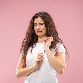 Junge Frau mit angeekeltem Gesichtsausdruck. Symbolbild zum Überblick: Schimmel an Lebensmitteln wie Brot, Obst oder Käse – was muss ich wegwerfen, was kann ich noch essen?