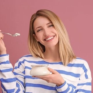 Junge Frau löffelt mit fragendem Blick einen Joghurt aus. Symbolbild fürs Grammatik-Quiz: Welcher Artikel ist in der deutschen Sprache richtig?