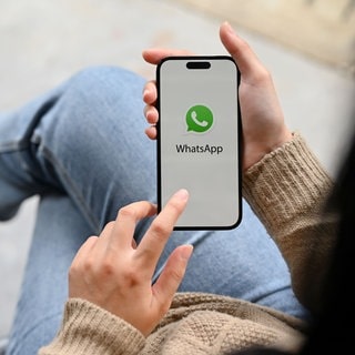 Junge Frau mit Smartphone in der Hand. Beim Messenger Whatsapp können Sprachnachrichten bald in Text umgewandelt und transkribiert werden.