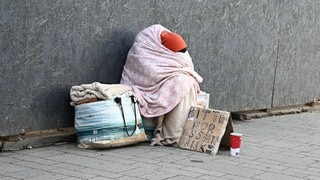 Obdachlose Person beim Betteln um Geldspenden und Sachspenden