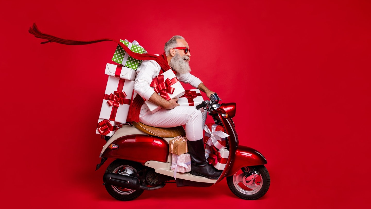 Ein Mann, der dem Weihnachtsmann ähnelt sitzt mit vielen Paketen auf einem Roller | So kommen eure Weihnachts-Pakete pünkltich an